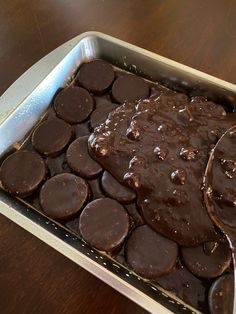 a pan filled with chocolate desserts on top of a wooden table