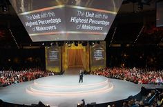 a man standing on top of a stage in front of a large group of people