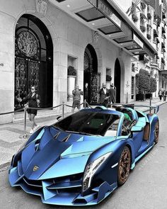 a blue sports car parked in front of a building on the side of a street