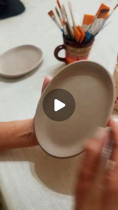 a person holding a white plate on top of a table with other plates and utensils