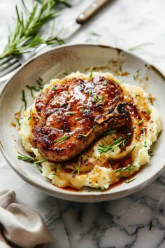 meat and mashed potatoes in a white bowl on a marble table with silverware