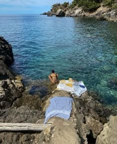 a man laying on top of a rock next to the ocean