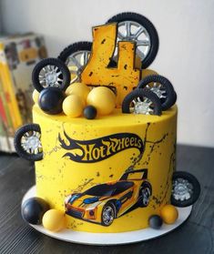 a yellow birthday cake with wheels and tires on it