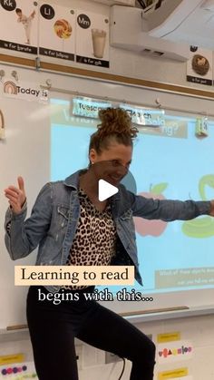 a woman standing in front of a projector screen giving a presentation to children at school