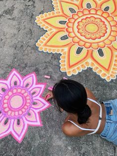 a girl is drawing on the ground with chalk and crayon markers in front of her