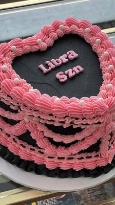 a heart shaped cake sitting on top of a white plate with pink icing and the words i love you spelled in large letters