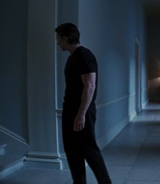 a man walking down a hallway in the dark