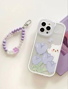 an iphone case with a lanyard and keychain attached to it, sitting next to a cell phone