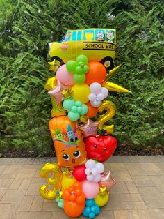 a bunch of balloons are stacked on top of each other in front of some bushes