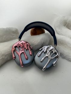 two silver and pink hair clips sitting on top of a white fur covered bed next to a stuffed animal