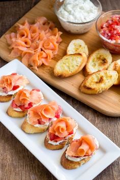 small appetizers are arranged on a plate with bread and tomato salad in the background