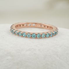 a rose gold ring with blue topaz stones on the inside and outside, sitting on a white surface