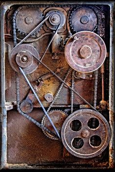 an old rusty machine with gears attached to it's sides and some other parts