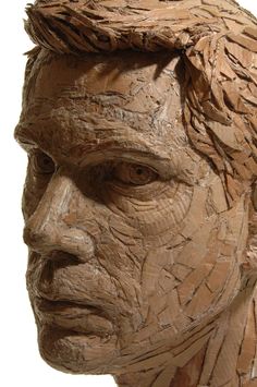 a close up of a sculpture of a man's face made out of wood