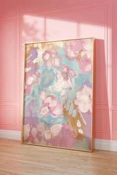 an abstract painting is displayed in front of a pink wall and wooden floor with light coming through the window