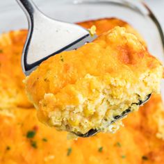 a spoon with some food on it in a casserole dish that is being held up