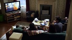 family sitting on couches watching tv in living room