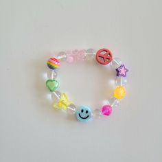 a bracelet with beads, charms and smiley faces on white table top next to wall