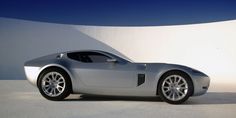 a silver sports car parked in front of a white wall with no one around it