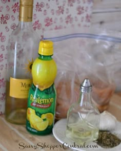 bottles and spices on a table next to an empty glass bottle with lemons in it