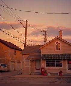 a small yellow building with a red fire hydrant in front of it at sunset