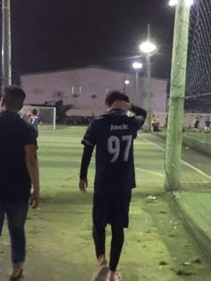 two men walking on a soccer field at night, one is wearing a jersey that reads 99