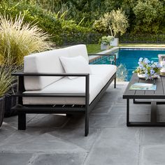 an outdoor living area with two couches and a coffee table next to a swimming pool