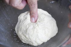 a person is kneading dough into a bowl with their finger in the middle