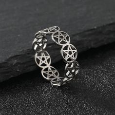 a silver ring with an inverted design on it, sitting on a black surface next to a