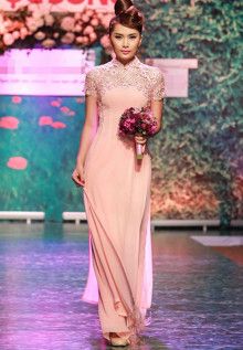 a woman is walking down the runway wearing a dress with flowers in her hair and holding a bouquet