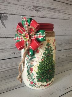 a jar with a christmas tree painted on the front and red ribbon tied around it