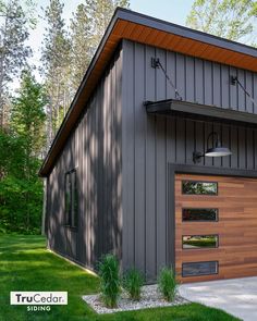 a garage with a large wooden door on the side and grass in front of it