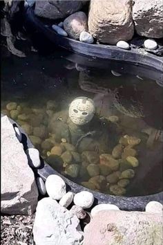 a rock garden pond with rocks around it and a ball in the water surrounded by stones