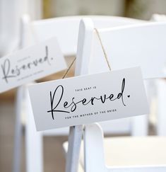 two white chairs with reserved signs attached to them