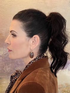 a woman with her hair in a pony tail style ponytail and wearing large hoop earrings