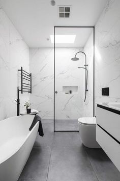 a modern bathroom with white marble walls and flooring, along with a freestanding bathtub