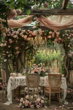 an outdoor dining area with tables and chairs covered in pink flowers, surrounded by greenery