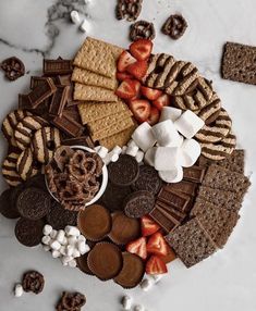 a platter filled with crackers, strawberries and other snacks on top of a marble table