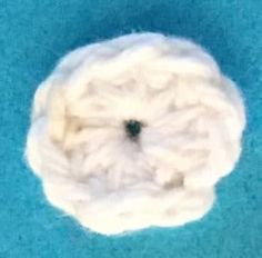 a white ball of yarn sitting on top of a blue surface with a black hole in the middle