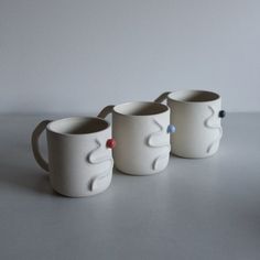 three white mugs sitting next to each other on a table