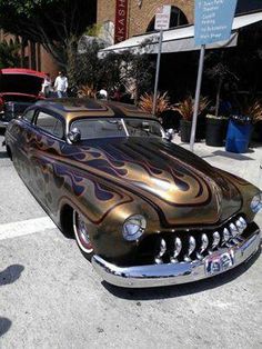 an antique car with flames painted on it's hood parked in a parking lot