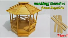 a small wooden gazebo sitting on top of a table next to popsicle sticks