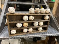 several baseballs are stacked on top of each other in a wooden crate with metal shelves