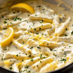 a pot filled with pasta covered in sauce and lemon wedges