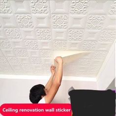 a man is painting the ceiling with white wall stickers and glues on it