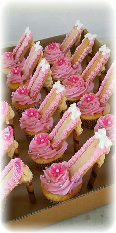 cupcakes with pink frosting and flowers are arranged in a box on the table