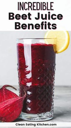 a glass filled with beet juice next to a sliced lemon