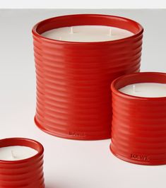 three red plastic containers with white candles in them