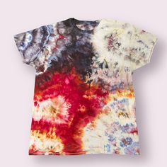 a tie dyed t - shirt with different colors and patterns on the front, sitting against a pink background