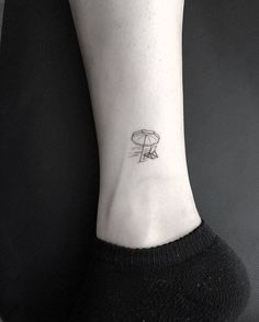 a small tattoo on the ankle of a woman's left foot with an umbrella